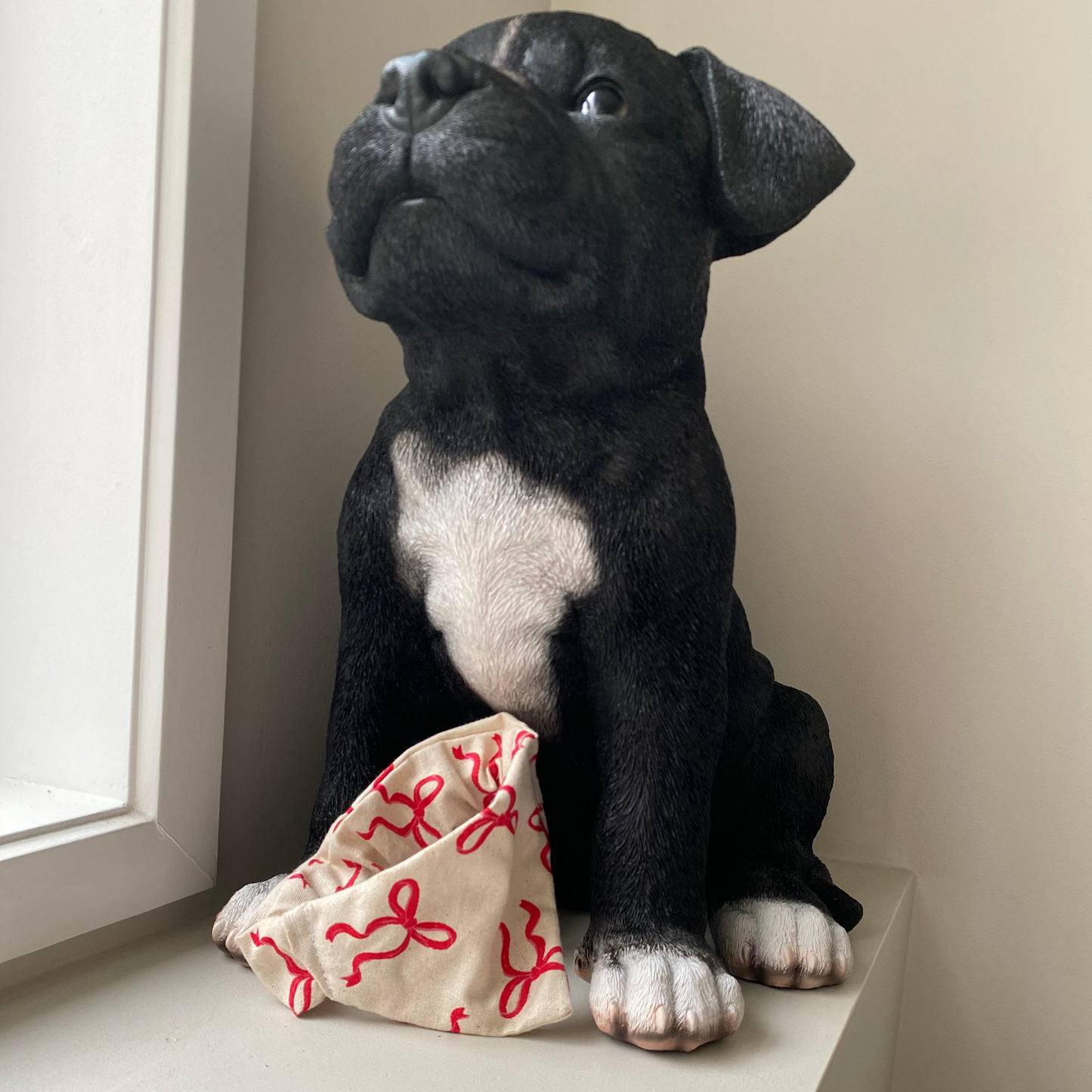 Black dog wearing a beige bandana with red bows on it