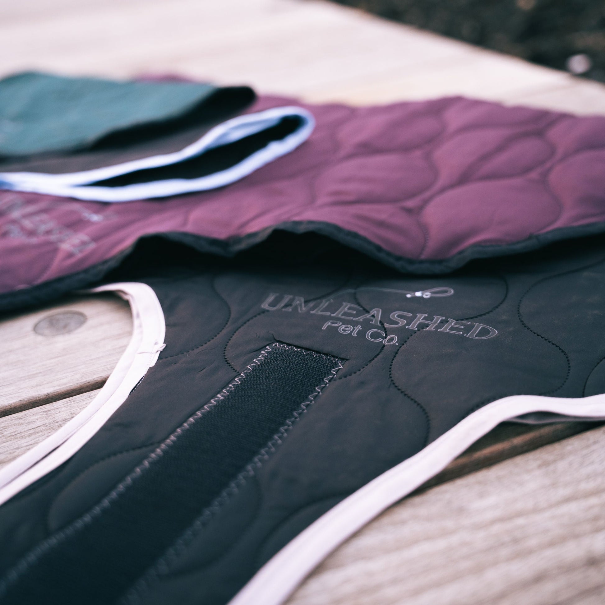 Quilted Dog jacket with 'Unleashed' branding placed on a wooden surface.