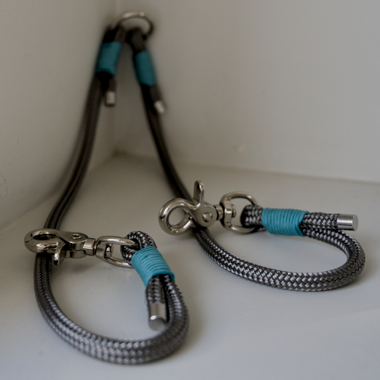 A dual dog attachment to connect to your dog leash. It is made from marine rope and has aqua paracord wrapped around the joins. The splitter is placed on a white background.
