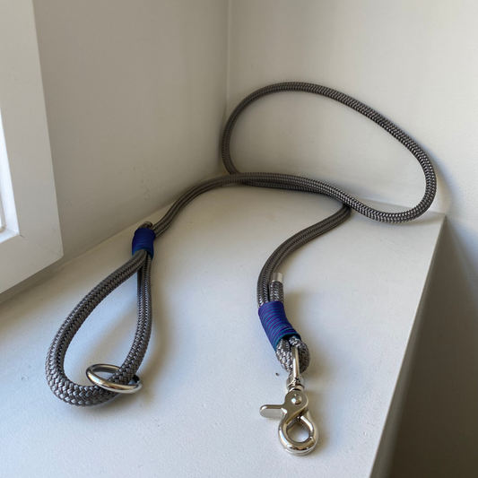 Grey rope dog leash with blue and purple accent on a white surface